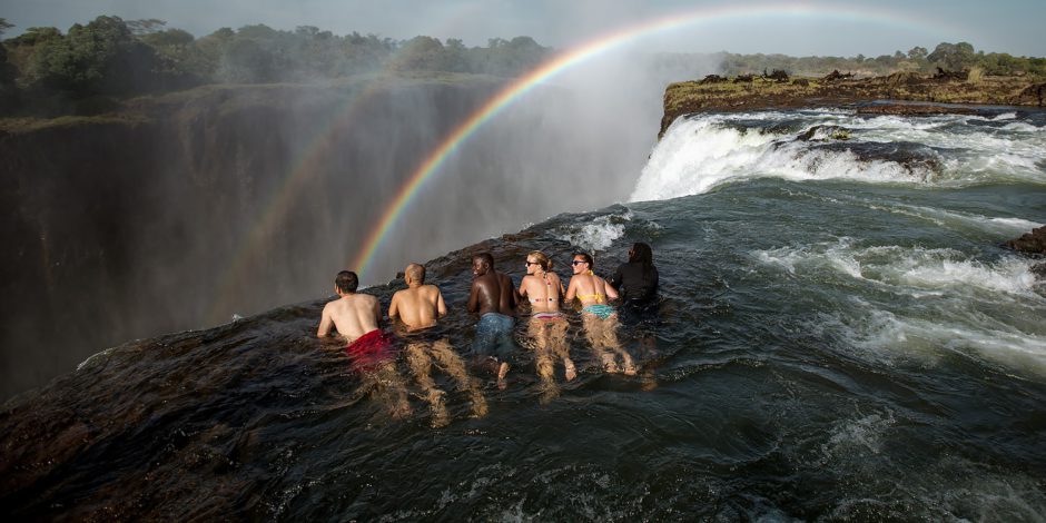 Un grupo al borde de la Piscina del Diablo, Crédito de la Imagen: Isla Livingstone